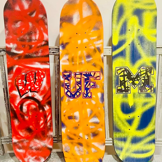 colorful skateboard decks with abstract designs and college names 
