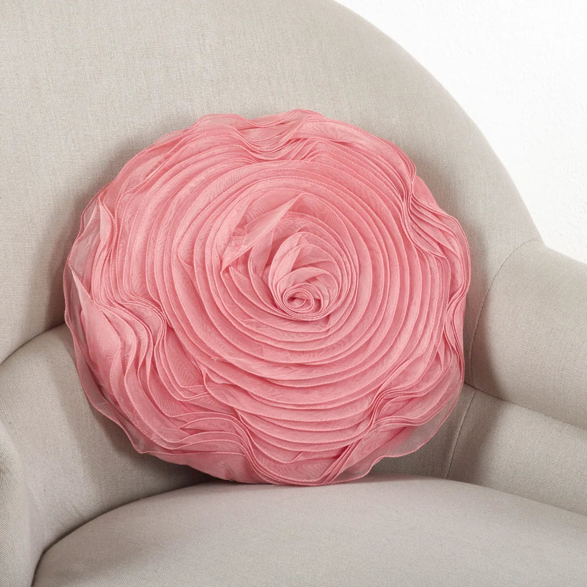 Round blush rose throw pillow with layered satin petals on a cream armchair, perfect for glam or coquette dorm décor