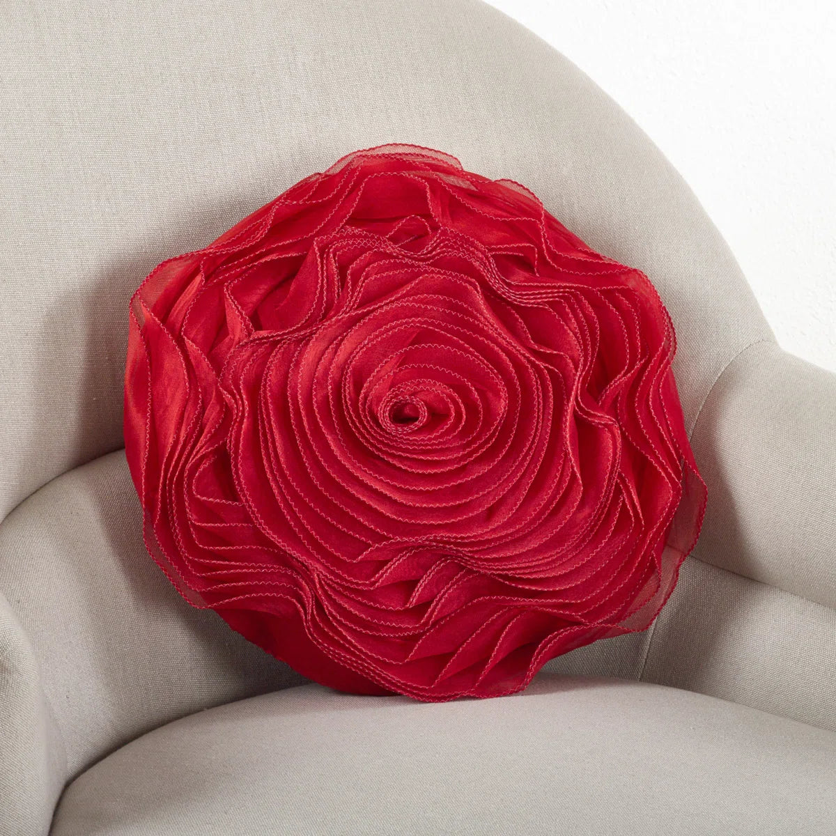 Round red rose throw pillow with layered satin petals on a cream armchair, perfect for glam or coquette dorm décor