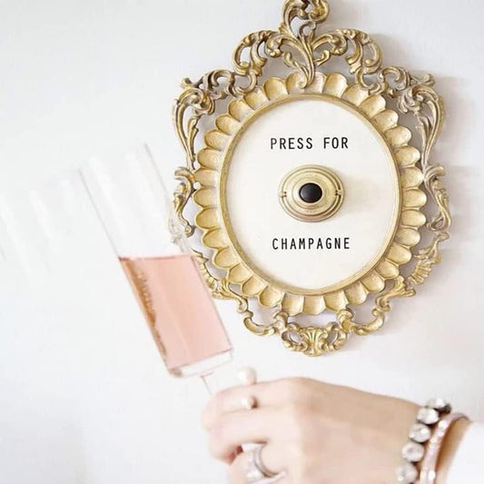 Ornate gold wall mirror with “Press for Champagne” detail, perfect for glam or blush dorm décor
